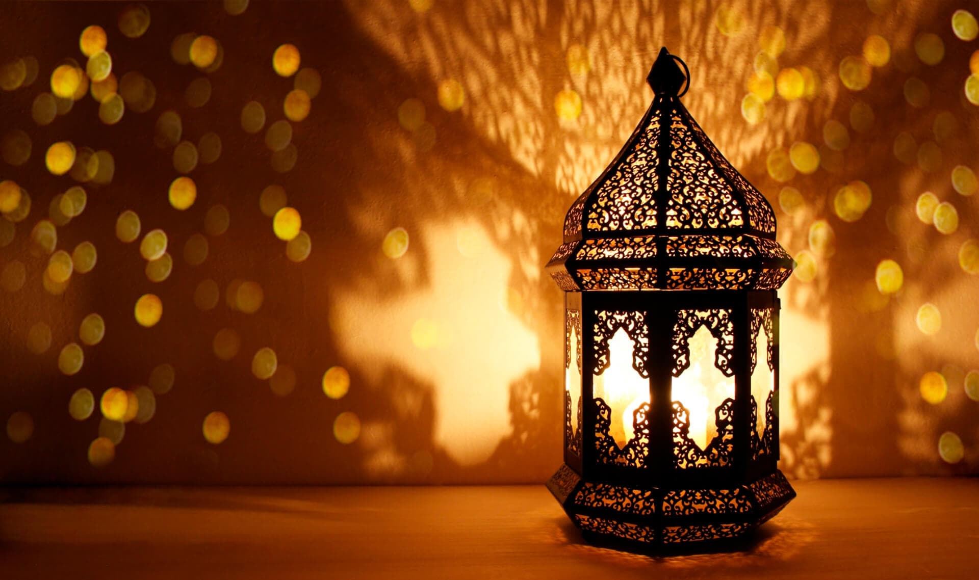 938430448-Ornamental-Arabic-lantern-with-burning-candle-glowing-at-night-and-glittering-golden-bokeh-lights.-Festive-greeting-card-invitation-for-Muslim-holy-month-Ramadan-Kareem-1-1